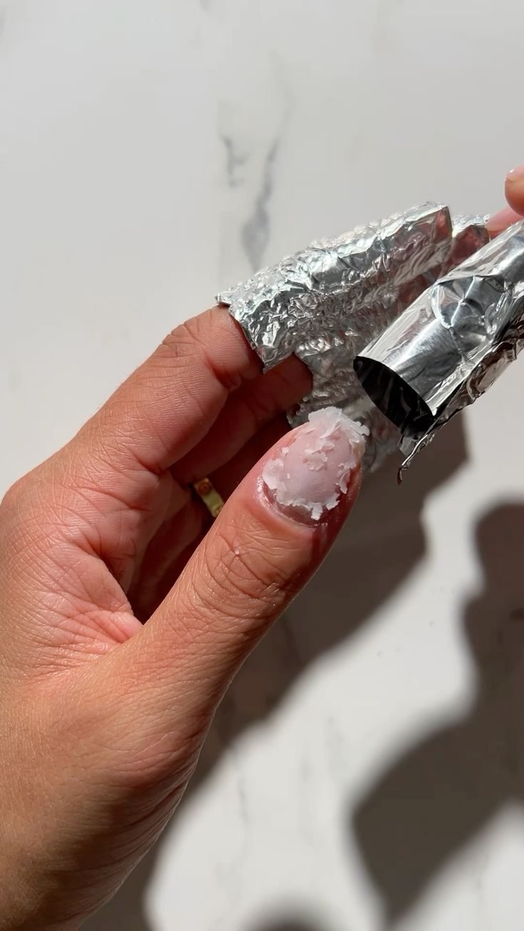 Gel wird mit Alufolie von einem Fingernagel gelöst